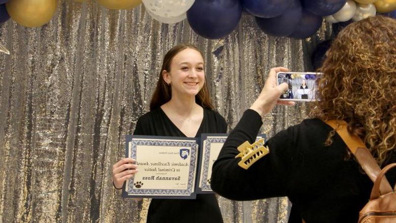 365英国上市杜波依斯分校 student Savannah Ross pauses with her awards for a photo, 由家庭成员拍摄, at the recognition and awards banquet at the PAW Center.